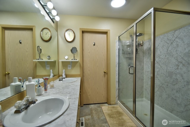 bathroom featuring a sink, a shower stall, and double vanity