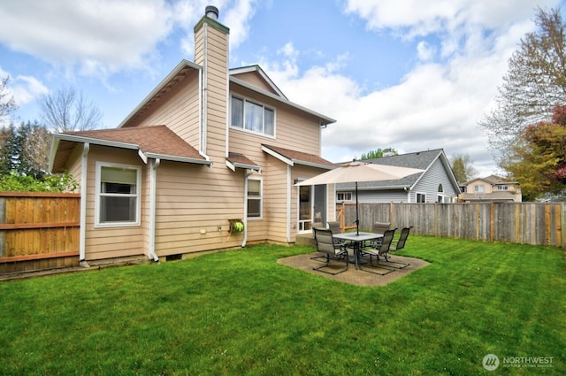 back of house with a fenced backyard, a chimney, a yard, and a patio