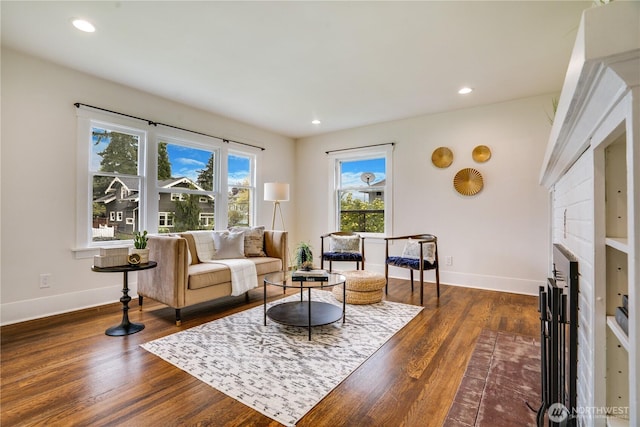 living room with baseboards, recessed lighting, a fireplace with flush hearth, and dark wood-style floors