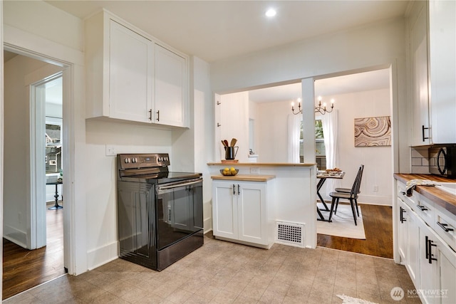 kitchen with visible vents, black electric range, baseboards, wood counters, and white cabinetry