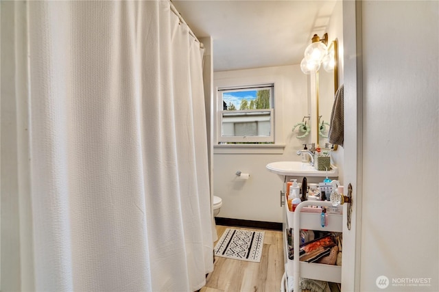 bathroom featuring a sink, baseboards, toilet, and wood finished floors