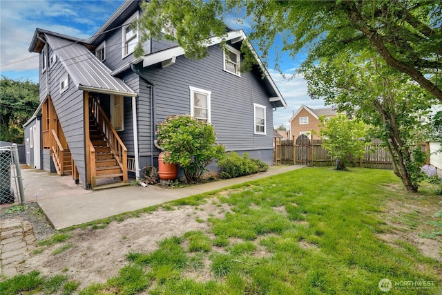 rear view of property featuring a lawn, fence, and stairs