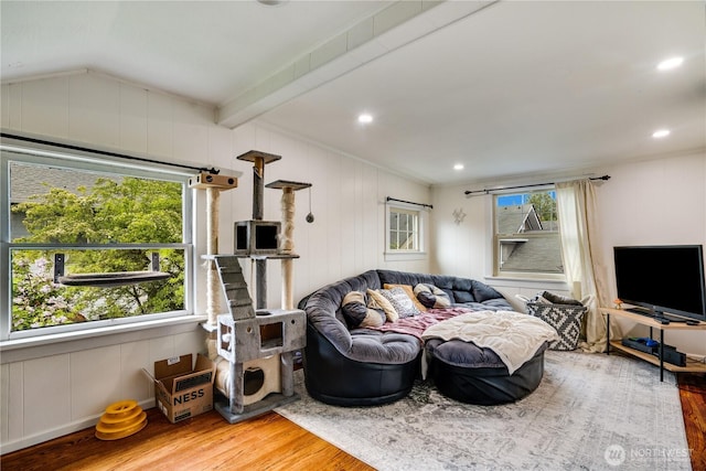 living area with crown molding, a decorative wall, wood finished floors, and lofted ceiling