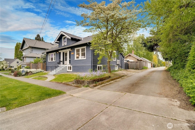 bungalow-style home with fence and a front yard