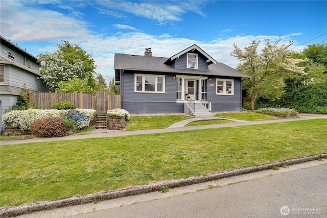 bungalow-style home with a front lawn, fence, and a chimney