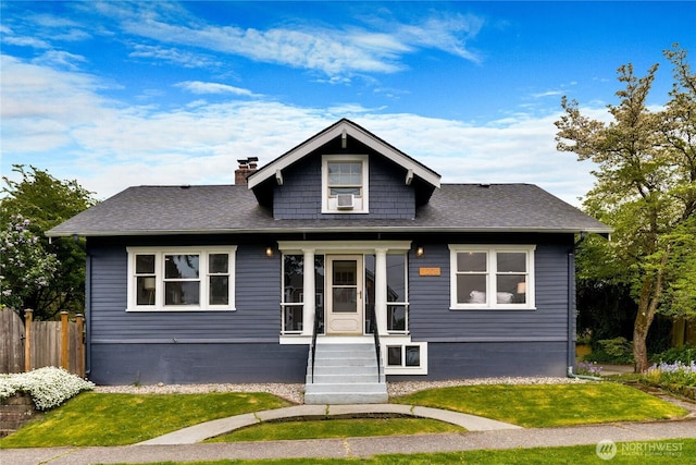 bungalow-style house featuring fence, a chimney, roof with shingles, and a front yard