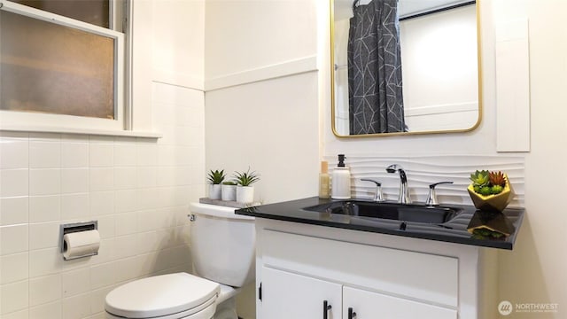 bathroom with toilet, tile walls, tasteful backsplash, and vanity
