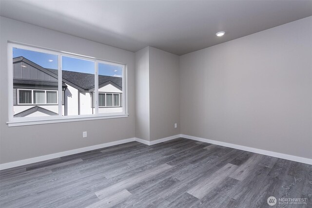 unfurnished room featuring recessed lighting, wood finished floors, and baseboards