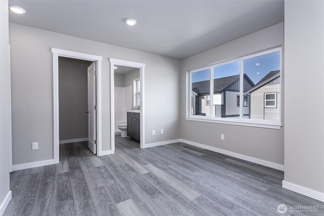 unfurnished bedroom with baseboards, wood finished floors, and a spacious closet