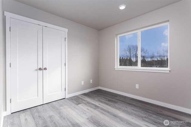 unfurnished bedroom featuring light wood-type flooring, baseboards, recessed lighting, and a closet