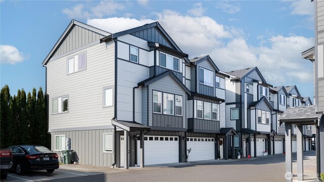 multi unit property with board and batten siding, a residential view, and a garage