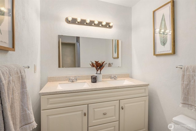 bathroom featuring double vanity and toilet