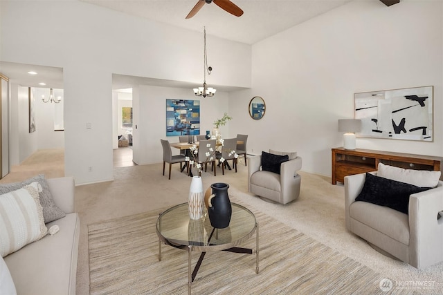 carpeted living area featuring a chandelier, a ceiling fan, and high vaulted ceiling