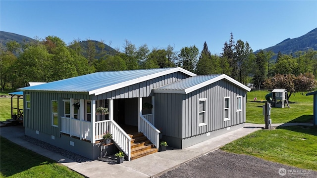 view of front of property featuring a front lawn, crawl space, a mountain view, covered porch, and metal roof