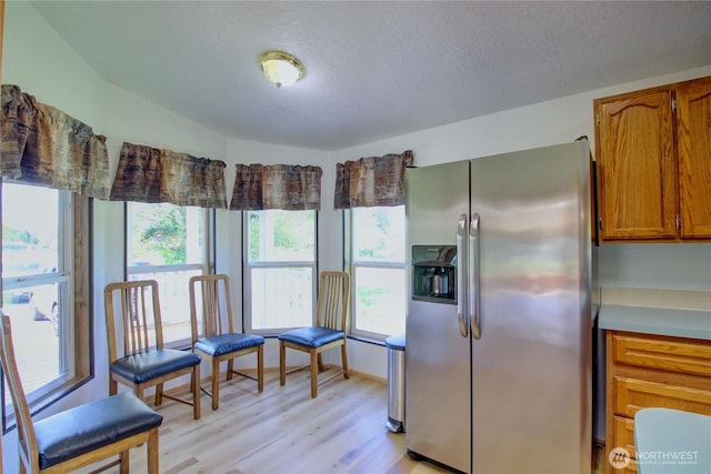 10029 Warfield Rd, Sedro Woolley, WA 98284 - kitchen with stainless steel fridge, light wood-style floors, brown cabinetry, a textured ceiling, and light countertops