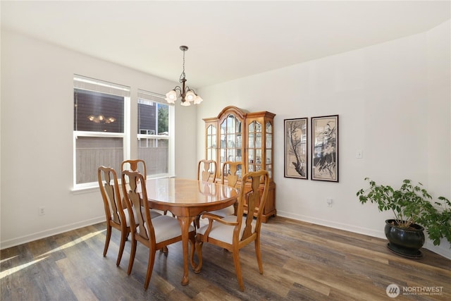 dining area with baseboards, an inviting chandelier, and dark wood-type flooring