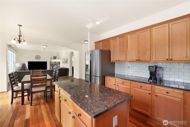kitchen with open floor plan, a chandelier, decorative backsplash, stainless steel fridge with ice dispenser, and dark wood-type flooring