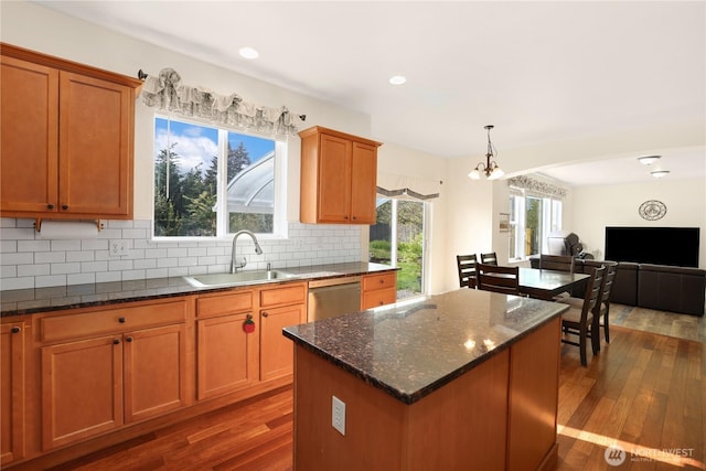 kitchen with a center island, dark stone countertops, a sink, decorative backsplash, and dark wood-style flooring