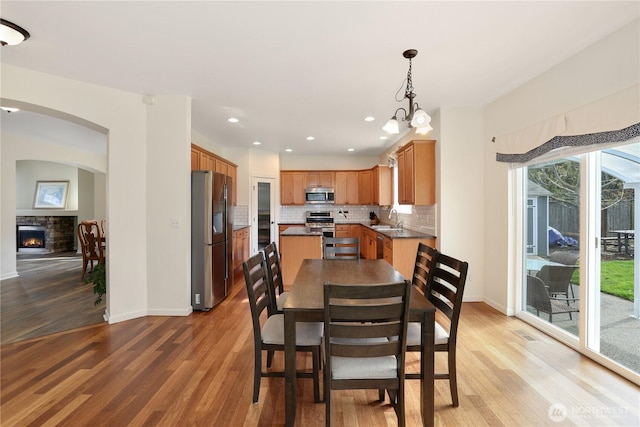 dining room with baseboards, a stone fireplace, and light wood-type flooring