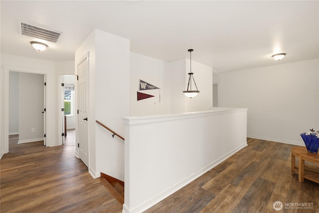 corridor featuring baseboards, dark wood-style flooring, an upstairs landing, and visible vents