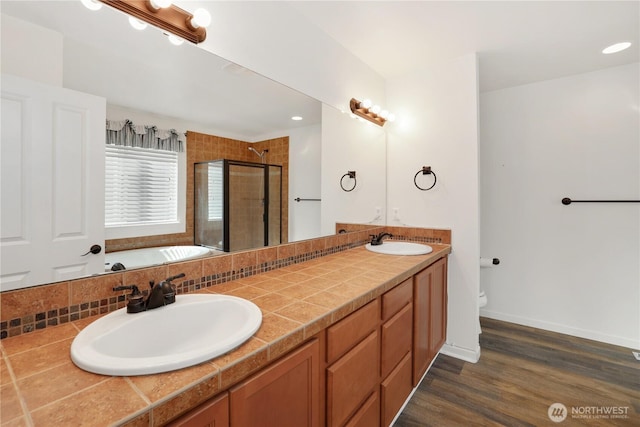 full bathroom with wood finished floors, a sink, a bathing tub, and a stall shower
