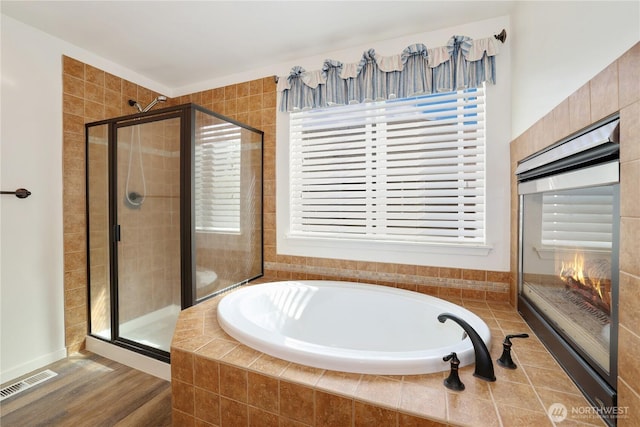 bathroom with a bath, a shower stall, visible vents, and plenty of natural light