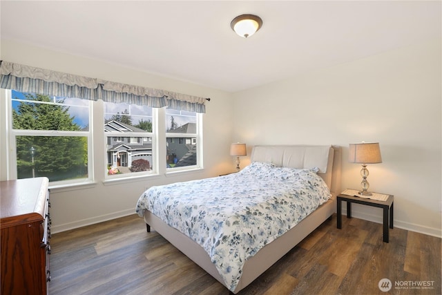 bedroom featuring wood finished floors, baseboards, and multiple windows