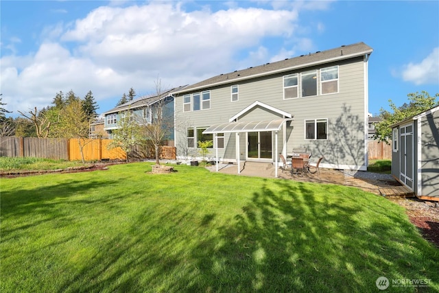 rear view of house with a fenced backyard, a yard, and a patio