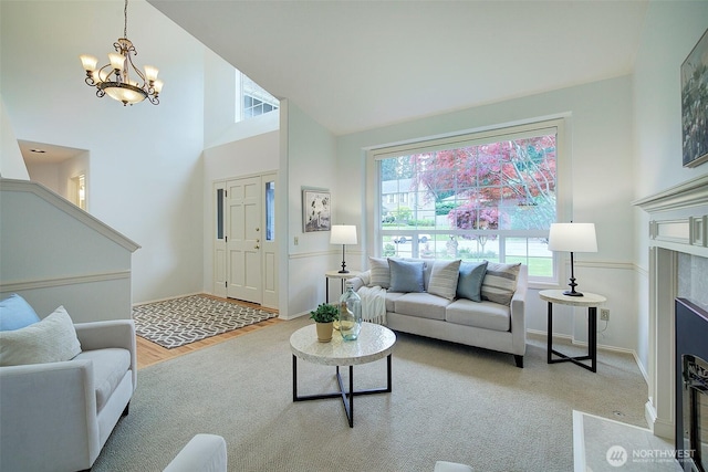 living area with baseboards, an inviting chandelier, and high vaulted ceiling