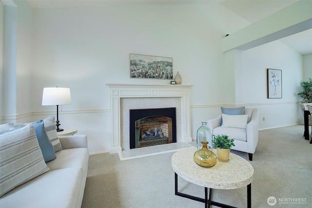 carpeted living area with baseboards, a fireplace with raised hearth, and lofted ceiling