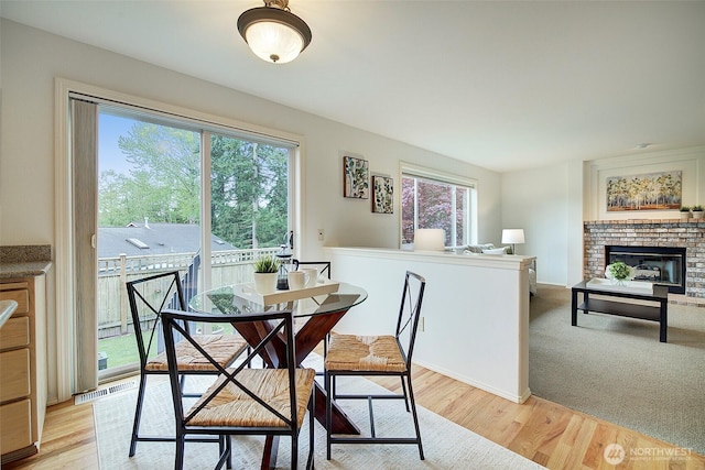 dining space with visible vents, light wood-style flooring, and a fireplace