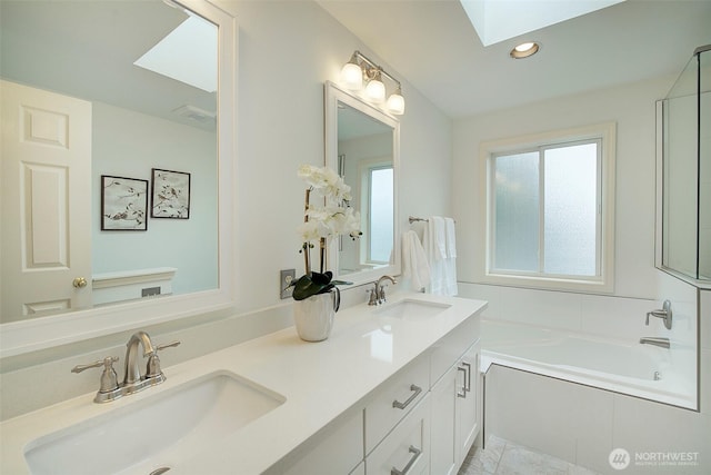 bathroom featuring double vanity, a skylight, a sink, and a bath