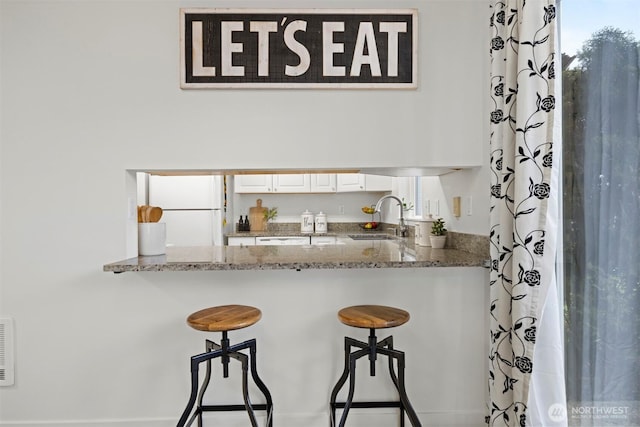 bar featuring white appliances, visible vents, and a sink