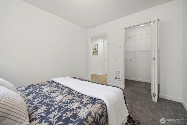 bedroom with carpet flooring, visible vents, baseboards, a closet, and a walk in closet