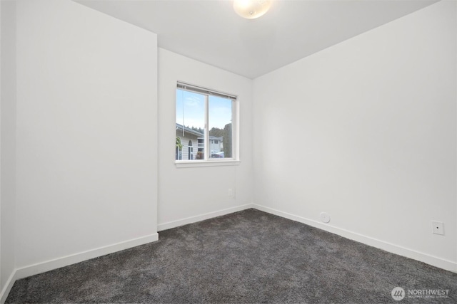 empty room featuring baseboards and dark colored carpet