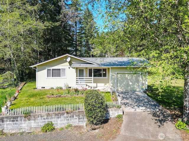 view of front of house with a fenced front yard, driveway, roof with shingles, a front yard, and an attached garage