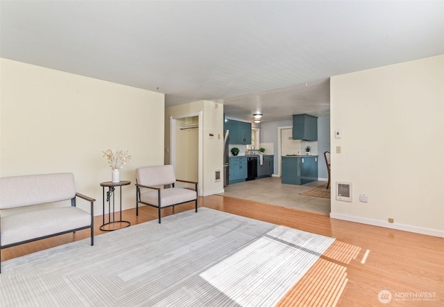 sitting room with visible vents, light wood-style flooring, and baseboards