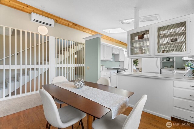 3837 Columbia Heights Rd, Longview, WA 98632 - dining space featuring a skylight, a wall unit AC, and wood finished floors