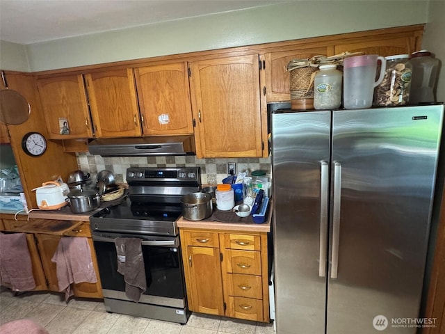 kitchen with under cabinet range hood, brown cabinets, appliances with stainless steel finishes, and light countertops