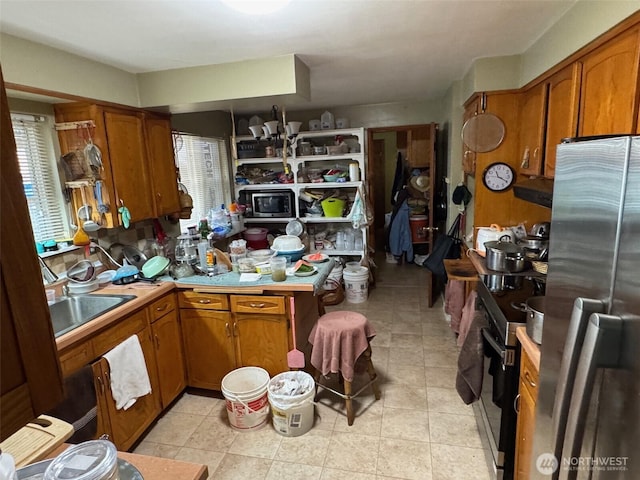 kitchen featuring brown cabinets, a peninsula, stainless steel appliances, and light countertops