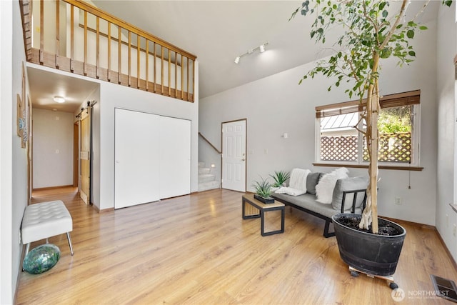 sitting room with high vaulted ceiling, wood finished floors, stairs, baseboards, and visible vents