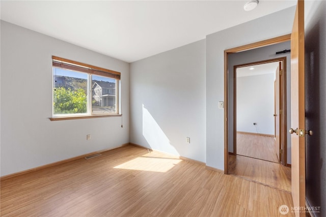empty room with baseboards, wood finished floors, and visible vents