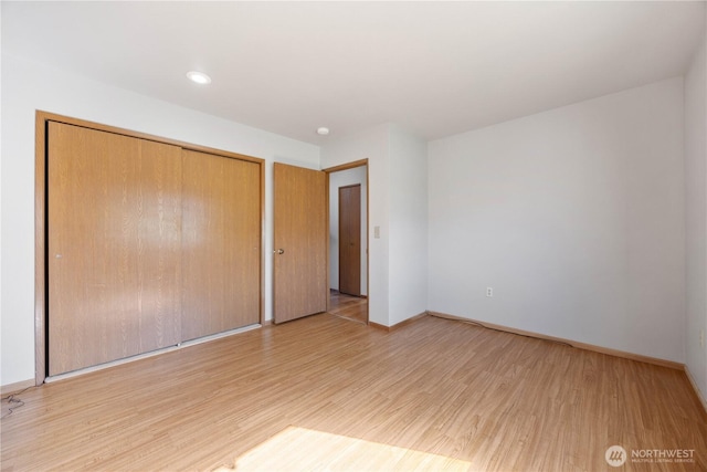 unfurnished bedroom with light wood finished floors, baseboards, and a closet