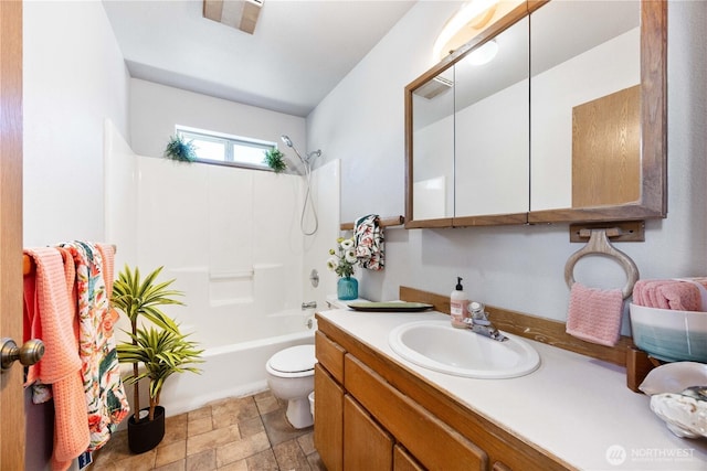 bathroom featuring shower / bathing tub combination, stone finish floor, toilet, and vanity