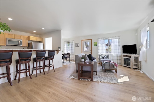 living room with recessed lighting, a healthy amount of sunlight, and light wood-style flooring