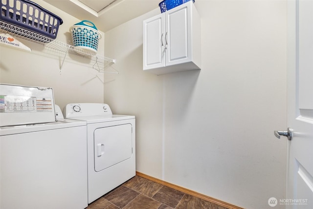 clothes washing area featuring baseboards, cabinet space, and washer and clothes dryer