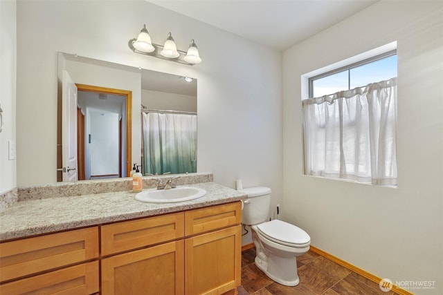full bath featuring toilet, vanity, and baseboards