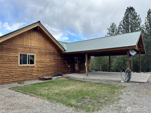 exterior space featuring metal roof, a front yard, a carport, and a patio