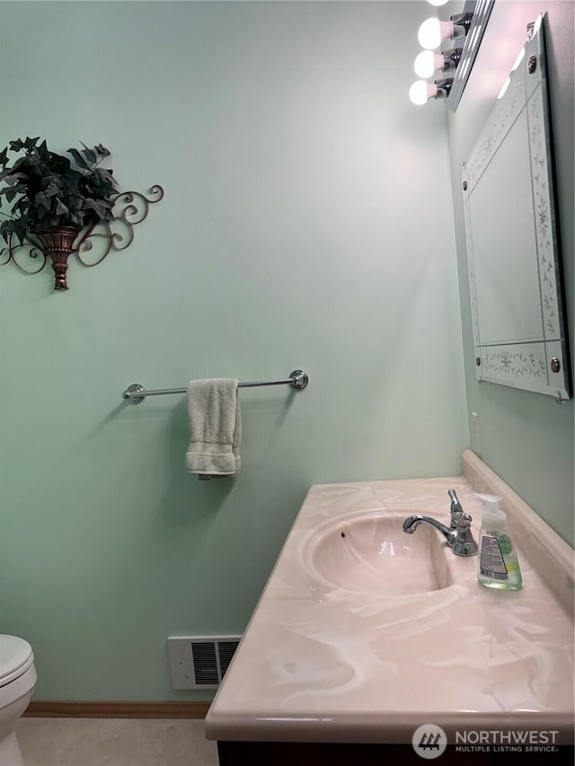 half bath with visible vents, toilet, and vanity