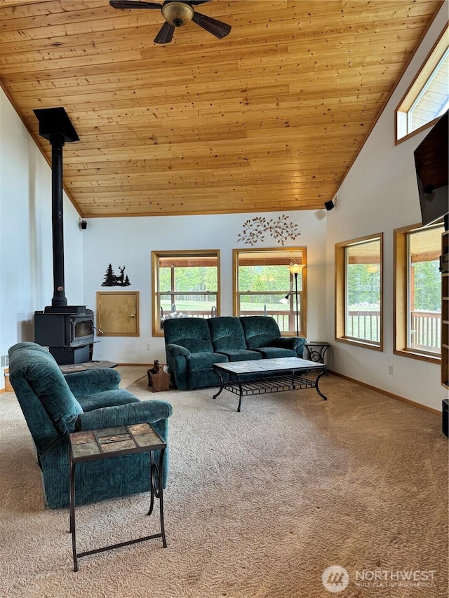 carpeted living area with a wood stove, wooden ceiling, ceiling fan, and a healthy amount of sunlight